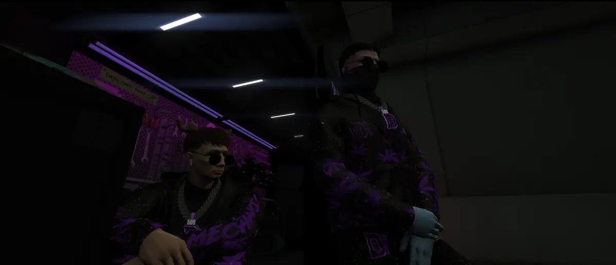 Two Drill UK mechanics in matching crew jackets inside their dimly lit garage